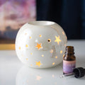 Quemador de wax melts redondo con motivo de estrellas, vista frontal sobre fondo claro, diseño artesanal elegante y decorativo