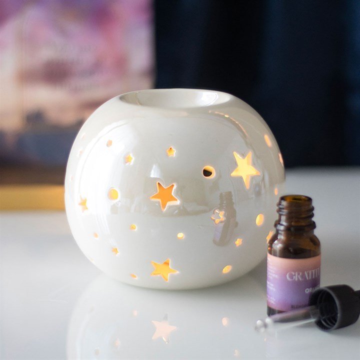 Quemador de wax melts redondo con motivo de estrellas, vista frontal sobre fondo claro, diseño artesanal elegante y decorativo